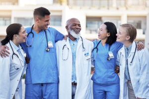 Group of healthcare workers with arms around one another three doctors and two nurses.