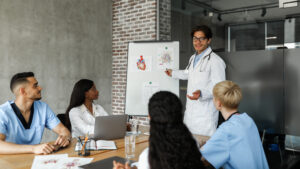 Doctor teaching medial students and nurses with diagram on board.