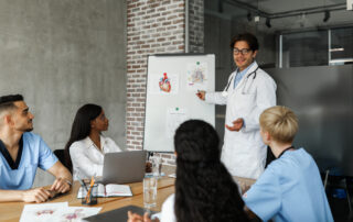 Doctor teaching medial students and nurses with diagram on board.