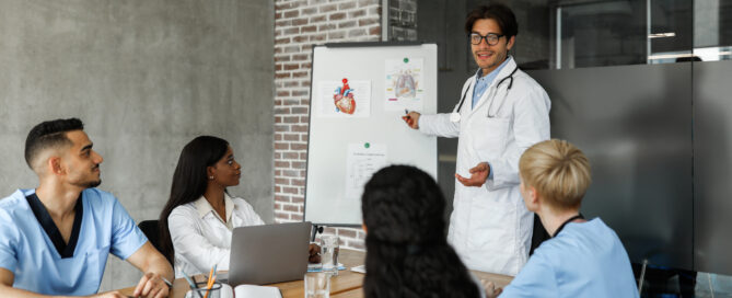 Doctor teaching medial students and nurses with diagram on board.