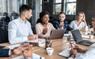 Group of professionals huddled around a confrence table looking at a women in the center