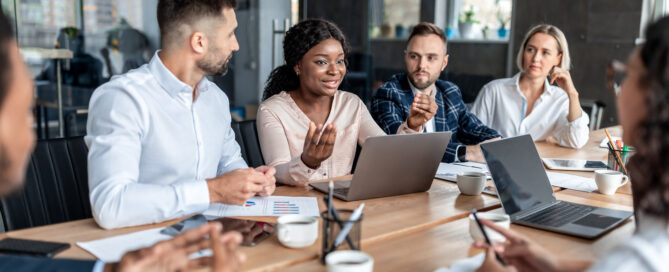 Group of professionals huddled around a confrence table looking at a women in the center